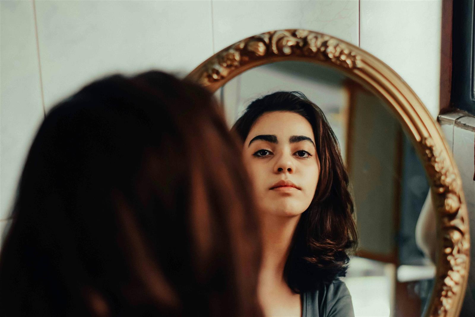 Woman looking in the mirror, finding her perfect hair color to complement her personal style